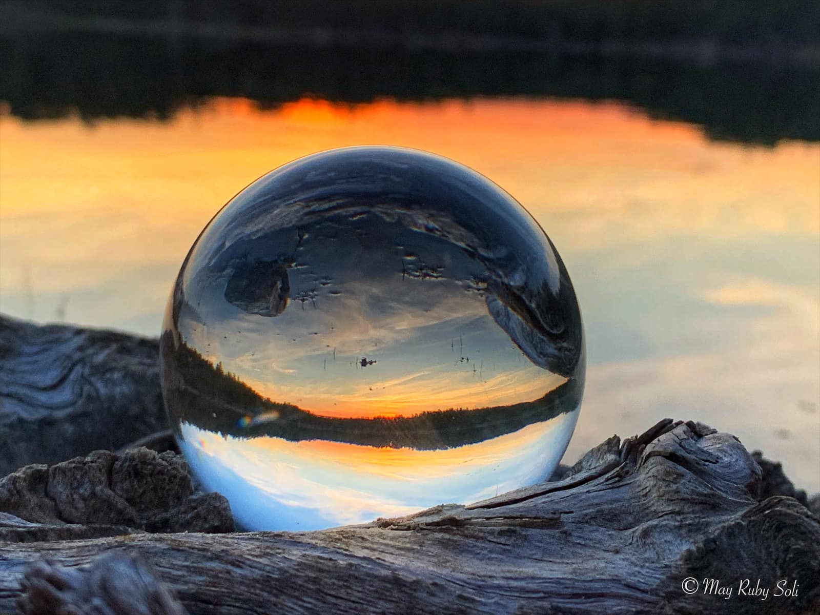 Solnedgang ved vannet sett gjennom en glasskule.