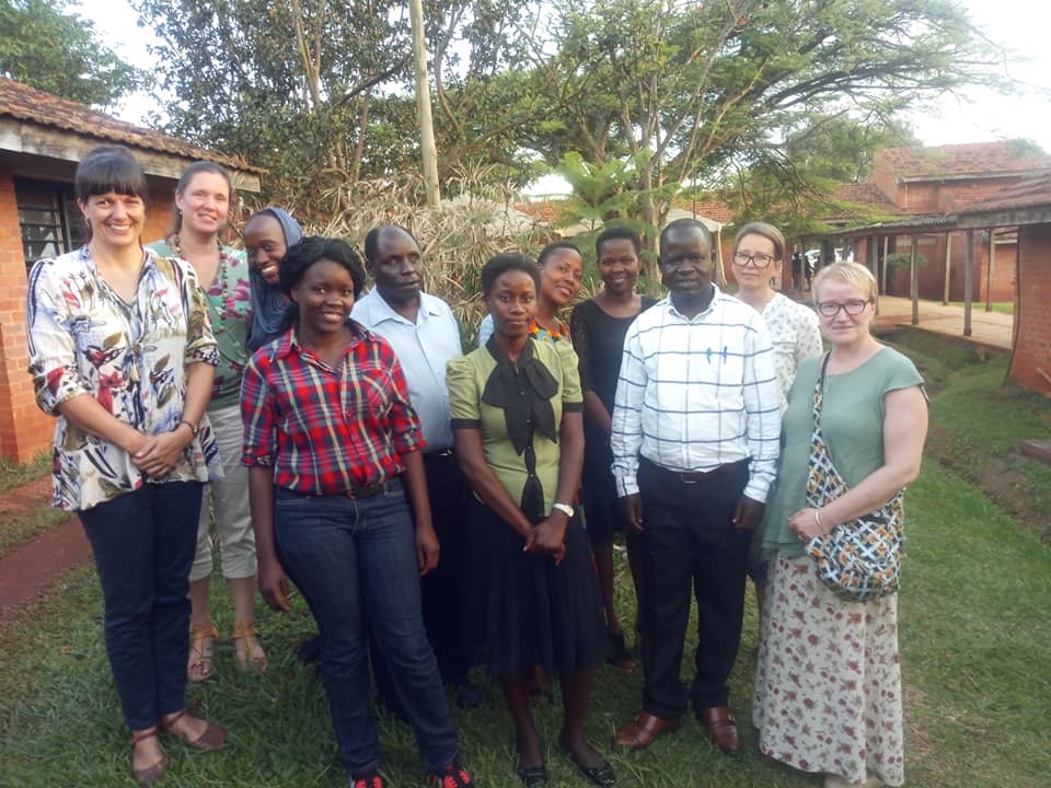 11 personer stående på gressplen i Uganda.