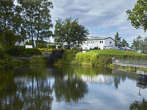 TRS, Sunnaas Sykehus. Hvit bygning med vann foran.
