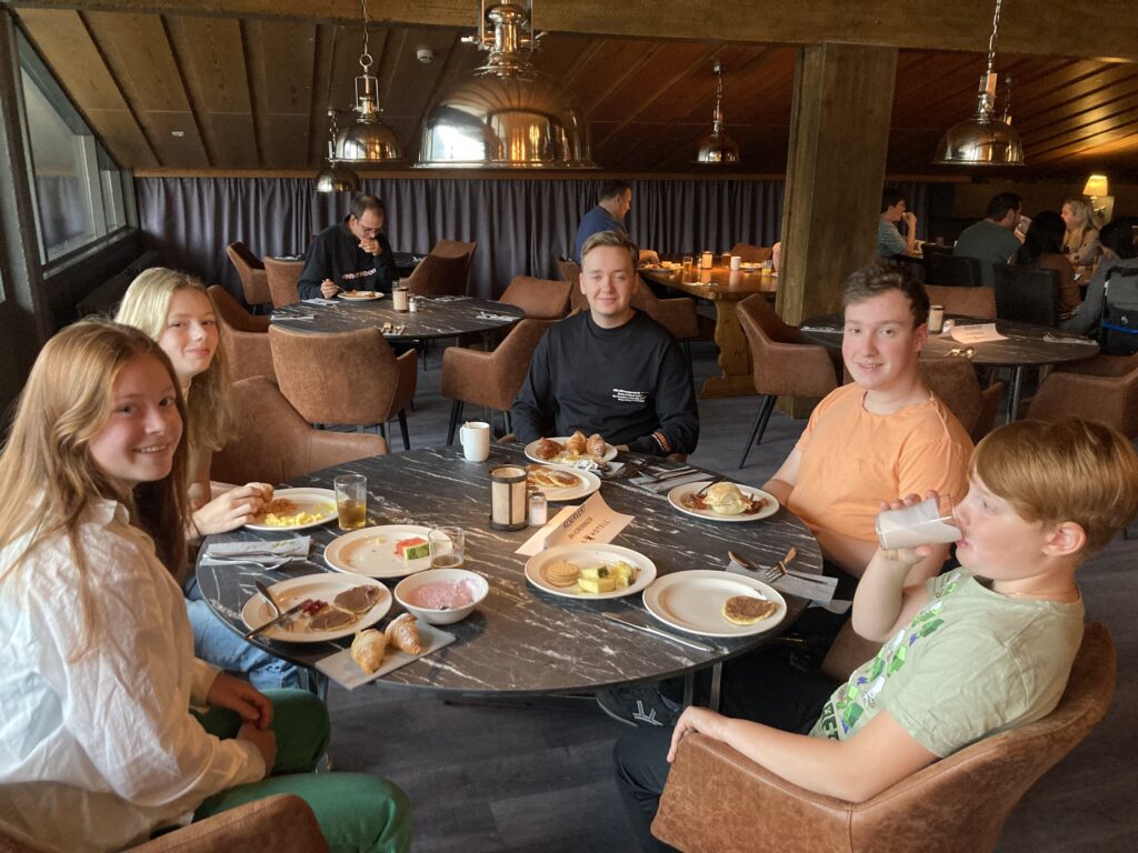 Unge medlemmer i RHØst sitter å spiser rundt et rundt bord i restauranten på Pers Hotell på Gol.