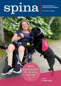 Forsidebilde Spina nr. 2 2021. Smilende kvinne i rullestol med service hund stående med forlabbene på hennes fang.