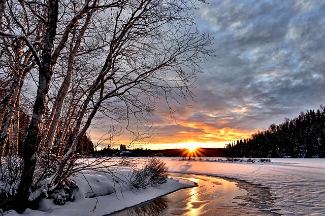 Winterlandskap. Grå skyer, men i horisonten ser en soloppgangen.