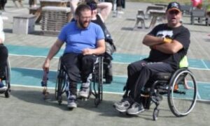 To voksne menn i rullestol i Skien Fritidspark. En dame i rullestol i bakrunnen.